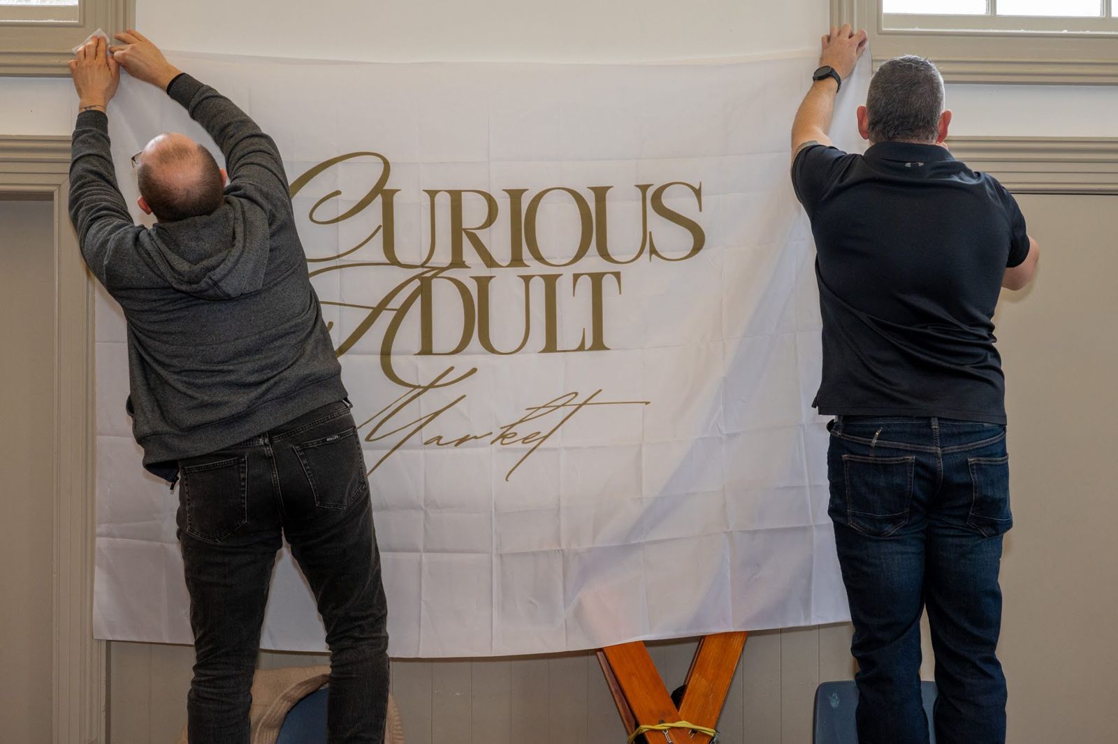 The team hanging the Curious Adult Market banner